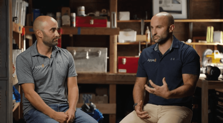 Meet founders Two men in matching polo shirts discussing in a workshop setting.