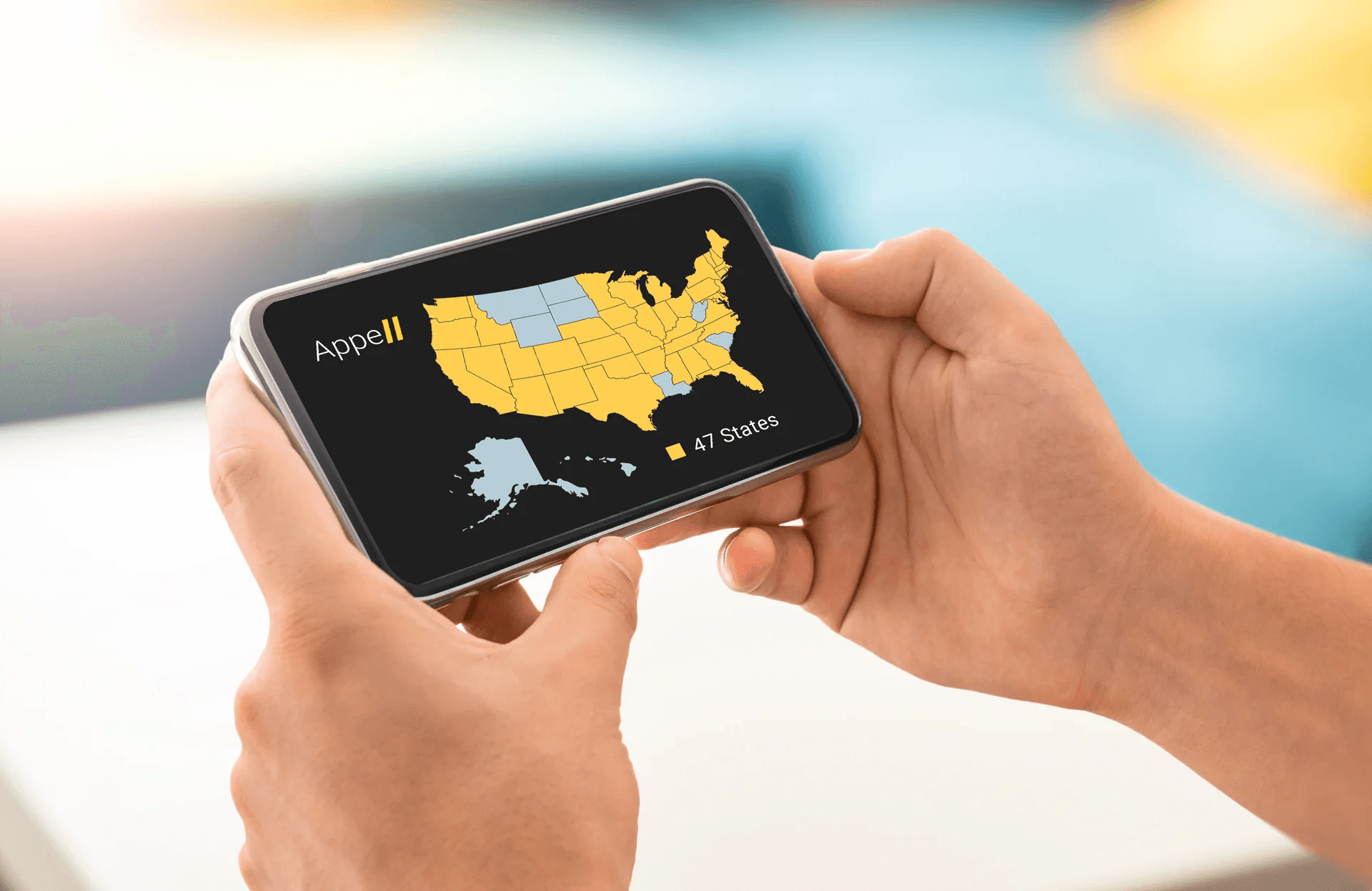 Process 01 Hands holding a smartphone displaying a map of the United States with 47 states highlighted in yellow.